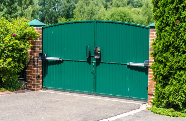 Motorised swing gate system installed by Auto Gate Guys Brisbane, featuring green double gates and brick pillars for a secure driveway entrance